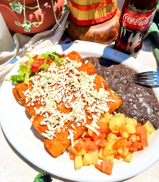 Enchiladas Rojas stuffed with Mexican cheese, queso fresco, and side of beans and potatoes