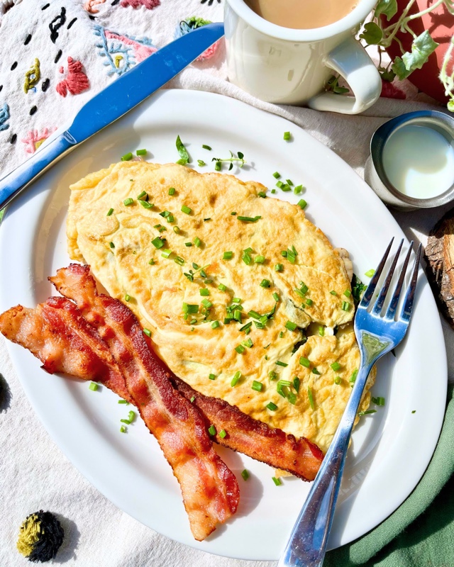 daily breakfast, omelet stuffed with mushrooms or spinach, onions and cheese, topped with chives and a side of meat